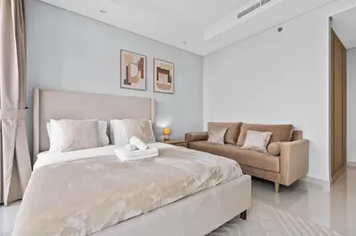 a white bedroom with a large bed and a couch at Luxury Stay with Burj Khalifa Views & Infinity Pool in Dubai