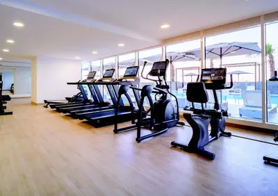 a gym with rows of treadmills and elliptical machines at Bohemian Bliss 1 BR Apartment in Dubai