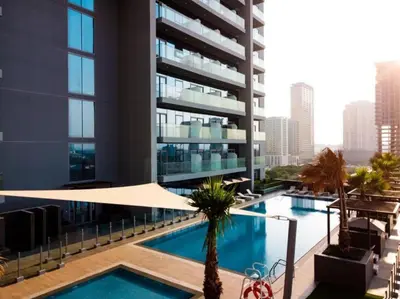 a large building with a swimming pool in front of a building at Bohemian Bliss 1 BR Apartment in Dubai
