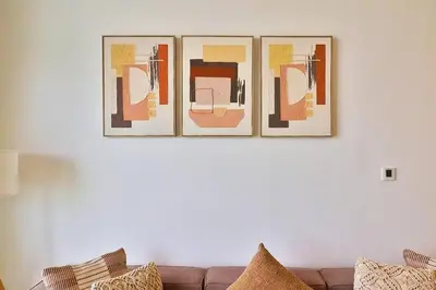 four pictures hanging on a wall above a couch at Bohemian Bliss 1 BR Apartment in Dubai