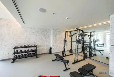 a gym with several rows of treadmills and weights at Charming 1BR Apartment at Marina Vista Tower 2 Emaar Beachfront Dubai Marina by Deluxe Holiday Homes in Dubai