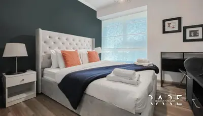 a bedroom with a large white bed with orange pillows at Rare Holiday Homes - Near Madame Tussauds - Goldcrest Executive - R3012 - Jumeirah Lake Towers in Dubai