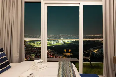 a bedroom with a large window with a view of a city at SmartStay at Carson Tower - Panoramic City Views - Modern Luxury Apartments in Dubai