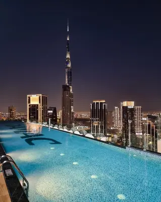 a swimming pool with a city skyline at night at Amazing 2BR Apartment in Paramount Hotel Midtown, 64th-Floor Infinity Pool & Burj Khalifa Views in Dubai