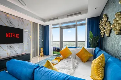 a living room with a blue couch and yellow pillows at Amazing 2BR Apartment in Paramount Hotel Midtown, 64th-Floor Infinity Pool & Burj Khalifa Views in Dubai