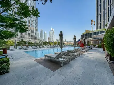 a pool with lounge chairs and umbrellas in a city at CitiHome-2BR at Address Opera in the Heart of Downtown in Dubai