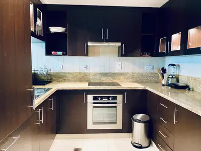 a kitchen with brown cabinets and a stove top oven at Greens in Dubai