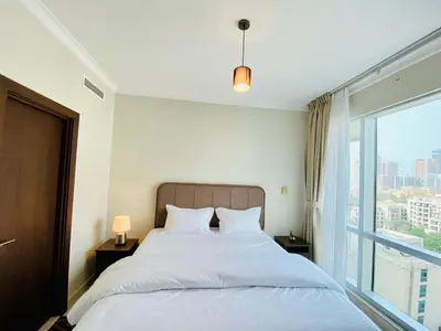 a bedroom with a bed and a large window at Greens in Dubai