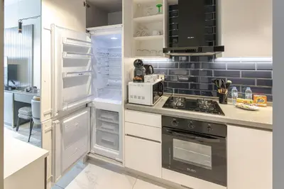 a kitchen with white cabinets and an open refrigerator at Elegant MAG 318 Studio Near Dubai Mall in Dubai