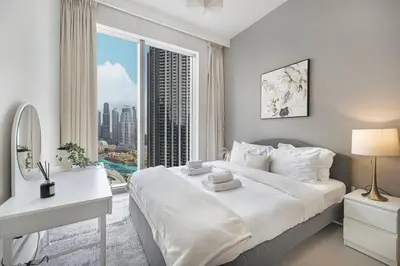 a bedroom with a bed and a desk and a window at Lux 3BR With Spectacular Downtown Views in Dubai