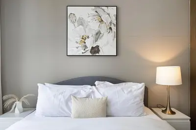 a bed with white pillows and a picture on the wall at Lux 3BR With Spectacular Downtown Views in Dubai