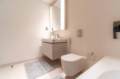 a white bathroom with a toilet and a sink at Luxury Sunrise Bay 1BR - Panoramic Sea View with Exclusive Amenities, by Think Realty in Dubai