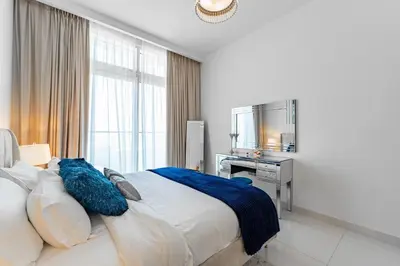 a bedroom with a large bed with blue pillows at Luxury Sunrise Bay 1BR - Panoramic Sea View with Exclusive Amenities, by Think Realty in Dubai