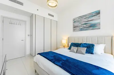 a bedroom with a large bed with blue pillows at Luxury Sunrise Bay 1BR - Panoramic Sea View with Exclusive Amenities, by Think Realty in Dubai