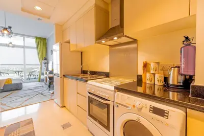 a kitchen with a stove and a washer and dryer at Elegant Studio in Damac Hills - Exclusive Living with Premium Amenities, Managed by Think Realty in Dubai