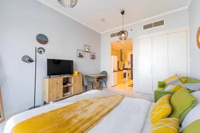 a living room with a bed and a television at Elegant Studio in Damac Hills - Exclusive Living with Premium Amenities, Managed by Think Realty in Dubai