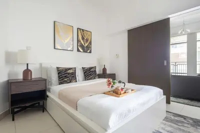 a white bedroom with a large bed with a tray of flowers on it at Frank Porter - The Lofts Central Tower in Dubai