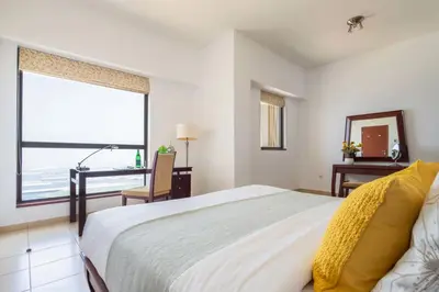 a bedroom with a bed and a desk and a window at Frank Porter - Sadaf 6 in Dubai