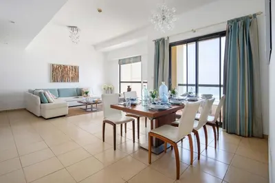 a dining room with a table and chairs and a couch at Frank Porter - Sadaf 6 in Dubai