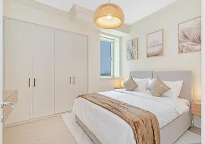 a white bedroom with a large bed and a chandelier at 2BR Dubai Marina Apt - Walk to Metro - Pool and Gym in Dubai