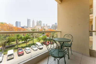 a balcony with a table and chairs and a view of a city at HAVN - 1 Bedroom in The Greens, Barsha Heights in Dubai