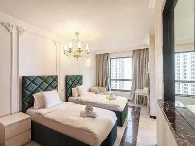 a hotel room with two beds and a chandelier at ELAN RIMAL MURJAN Suites in Dubai
