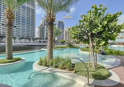 a swimming pool with palm trees in a resort at Luxurious 1 Bed in Dubai Creek Harbor, Hosted by Desert City Stays in Dubai