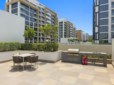 a patio with a table and chairs and buildings at Lovely Studio with Gym, Pool and BBQ Facilities in Dubai