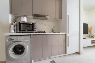 a kitchen with a washing machine and a microwave at Lovely Studio with Gym, Pool and BBQ Facilities in Dubai