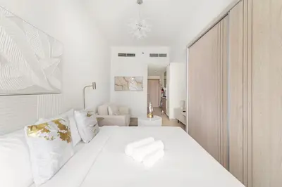 a bedroom with a white bed and a bathroom at Lovely Studio with Gym, Pool and BBQ Facilities in Dubai