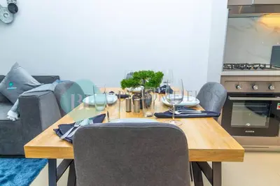 a dining room table with chairs and a table with wine glasses at Bloomfields 1br Azizi Gardens Meydan in Dubai