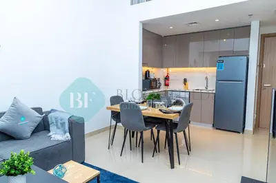 a living room with a couch and a table and a kitchen at Bloomfields 1br Azizi Gardens Meydan in Dubai