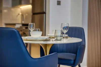 a table with two blue chairs and wine glasses at Elegant studio in Me Do Re Tower in Dubai