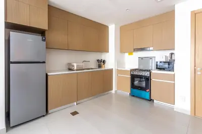 a kitchen with wooden cabinets and a refrigerator at Elegant 1 Bedroom at Creek Beach Bayshore in Dubai