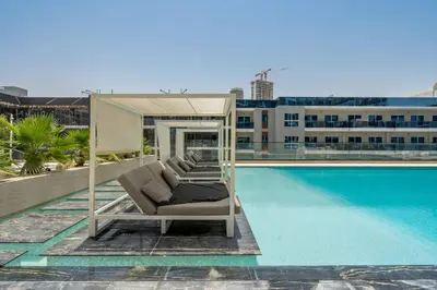a group of lounge chairs next to a swimming pool at GuestReady - Charming haven at Binghatti Crest in Dubai