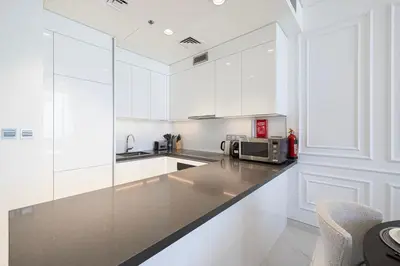 a kitchen with white cabinets and a counter with a microwave at Crystal Lagoon View Beach access Fast Wi-Fi in Dubai