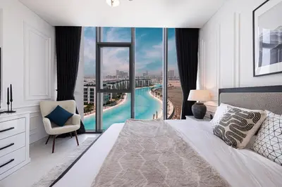 a bedroom with a bed and a view of a pool at Crystal Lagoon View Beach access Fast Wi-Fi in Dubai