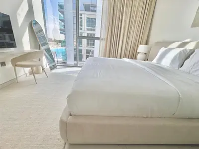 a bedroom with a white bed and a large window at Residences 29 - Divine Beachfront One Bedroom in Dubai