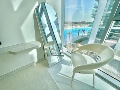 a white chair in a room with a large window at Residences 29 - Divine Beachfront One Bedroom in Dubai