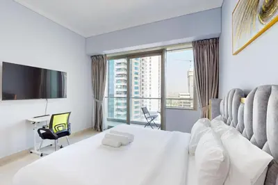 a bedroom with a white bed and a large window at Ocean Heights - Exquisite One Bedroom in Dubai