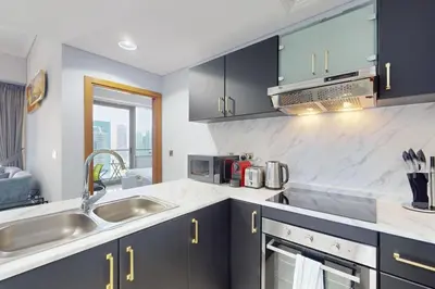 a kitchen with black cabinets and a sink at Ocean Heights - Exquisite One Bedroom in Dubai