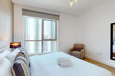 a bedroom with a white bed and a large window at Bay Central - Enticing Two Bedroom in Dubai