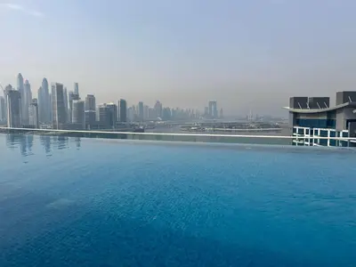 a large swimming pool with a city in the background at SevenPalm 2BR SeaView RooftopPool privBeach in Dubai