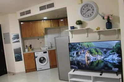a kitchen with a tv on a stand with a clock at Newly furnished 1 Bedroom, high floor, amazing view, close to metro in Dubai