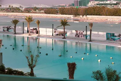a large swimming pool next to a beach with palm trees at Full Lagoon View Beach Access Exclusive building in Dubai