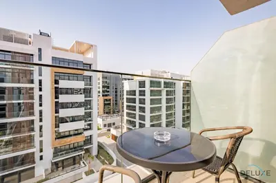 a table and chairs on a balcony with buildings at Attractive Studio Apartment in Azizi Riviera 15, Al Merkadh by Deluxe Holiday Homes in Dubai