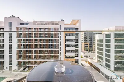 a glass table on a balcony with a view of buildings at Attractive Studio Apartment in Azizi Riviera 15, Al Merkadh by Deluxe Holiday Homes in Dubai