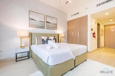 a bedroom with a large white bed with two lamps at Attractive Studio Apartment in Azizi Riviera 15, Al Merkadh by Deluxe Holiday Homes in Dubai