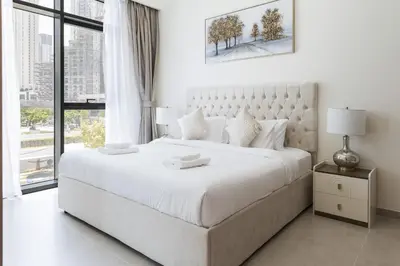 a white bedroom with a large white bed and a window at Elegant 1 bedroom in Creek Edge in Dubai