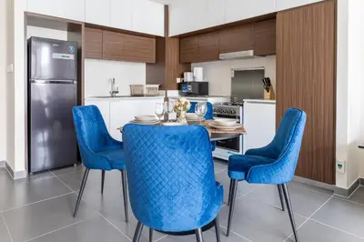 a kitchen with a table and blue chairs in a kitchen at Elegant 1 bedroom in Creek Edge in Dubai